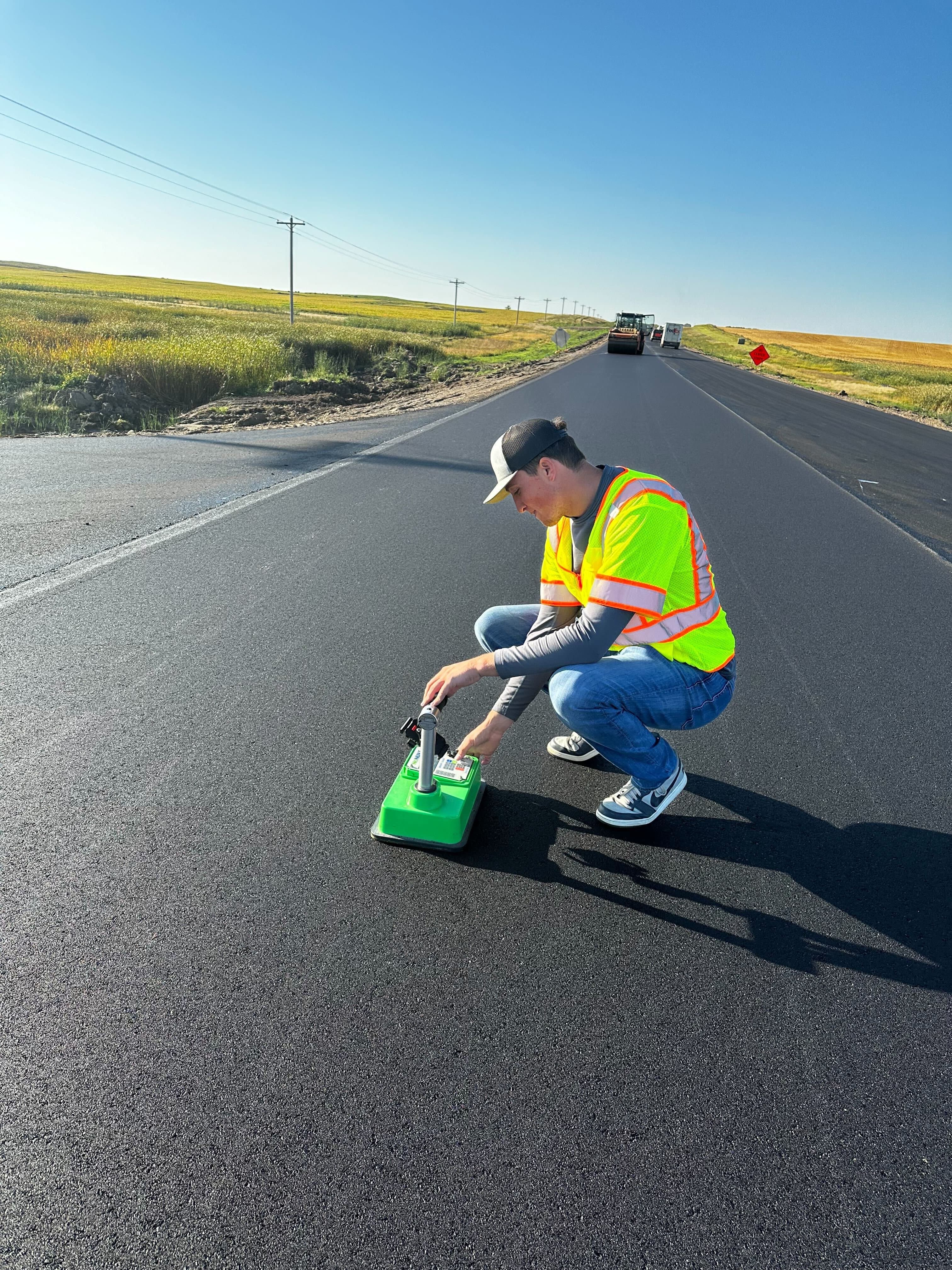 Construction worker taking density measurements on fresh asphalt